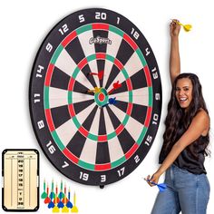 a woman standing next to a dart board and darts