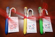 four christmas candy canes tied to red ribbon on a table with gift tags attached