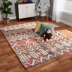 a teddy bear sitting on top of a colorful rug