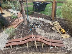 a garden area with wooden planks and rocks in the ground next to a tree