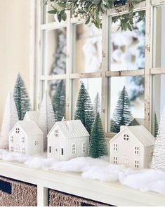 a christmas scene with white houses and trees in front of a window on a shelf