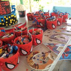 spiderman themed birthday party supplies on a table with cake and cupcakes in the background