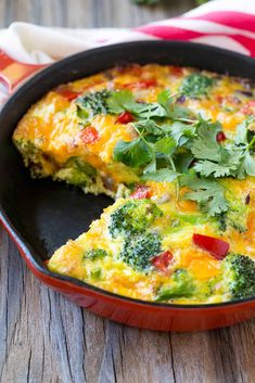 an omelet with broccoli and red peppers in a black skillet