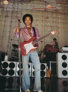 a man standing in front of a microphone and guitar