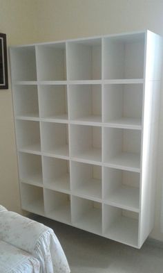 a white bookcase sitting next to a bed in a bedroom