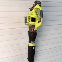 a yellow and black cordless device mounted to the side of a garage door next to a white wall