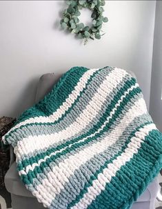 a green and white crocheted blanket sitting on top of a chair next to a wreath