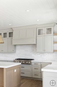 an empty kitchen with white cabinets and wood flooring on the countertops, along with a large island