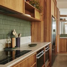 a kitchen with wooden cabinets and marble counter tops, along with green tile backsplash