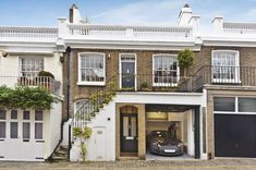 a car parked in front of a building with two garages on each side and stairs leading up to the second floor