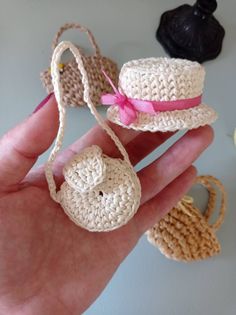 small crocheted hats are being held in someone's hand with other items nearby