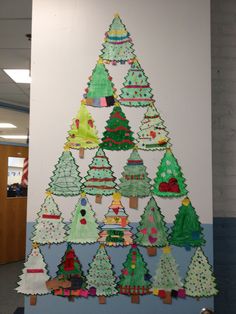 a christmas tree made out of paper on a wall in an office cubicle area