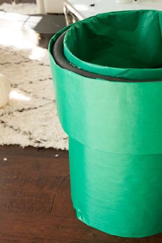 a large green pot sitting on top of a wooden floor next to a white rug