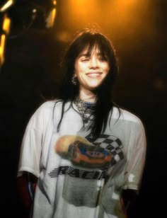 a woman with long black hair standing in front of a microphone and wearing a t - shirt