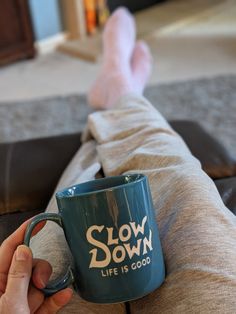 a person holding a coffee mug with the words slow down life is good on it