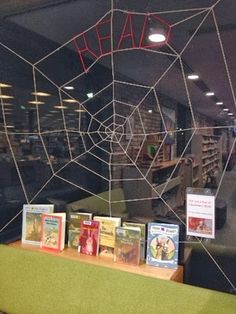 there is a spider web in the window with children's books on display behind it