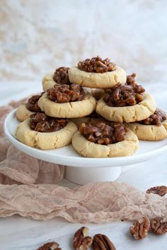 pecan cookies with chocolate filling on a white platter, surrounded by pecans