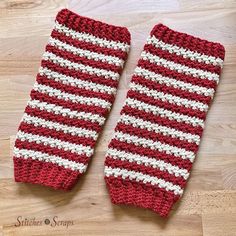 two red and white crocheted mitts sitting on top of a wooden floor