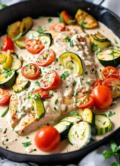 a pan filled with chicken, cucumbers and tomatoes covered in ranch dressing sauce