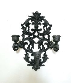 an ornate wall mounted candle holder on a white wall