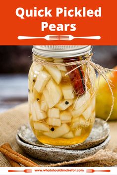 a mason jar filled with pickled pears on top of a table next to apples and cinnamon sticks