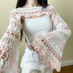 a woman wearing white pants and a pink crochet shawl over her shoulders