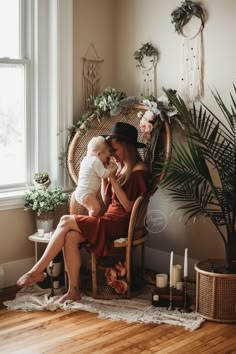 a mother and her baby sitting in a wicker chair with candles on the floor