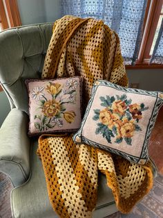 three pillows and a blanket on a chair