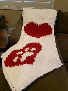 a crocheted blanket with lips on it sitting on a couch in front of a window