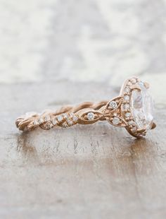 a close up of a ring on a wooden surface with diamonds in the band and an oval shaped center stone