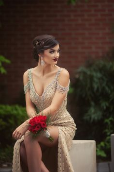 a woman sitting on top of a bench wearing a dress and holding a red rose