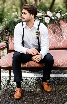 a man sitting on top of a pink couch in front of flowers and greenery