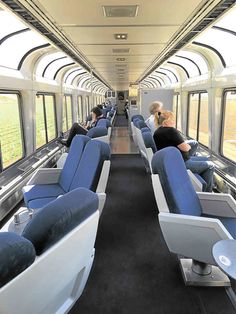 people are sitting on seats in the middle of an empty train car that is parked next to each other