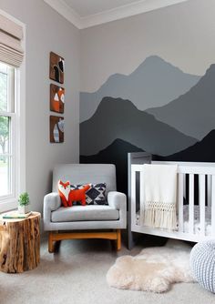 a baby's room with mountains painted on the wall and a white crib