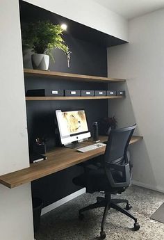 a desk with a monitor and keyboard on it in front of a wall mounted bookshelf