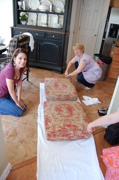 two women are doing something in the living room while another woman is working on some furniture