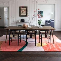 a dining room table with chairs and a rug on the floor in front of it