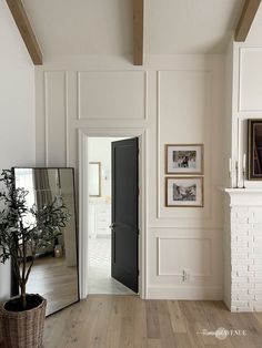 a living room with white walls and wood flooring next to a mirror on the wall