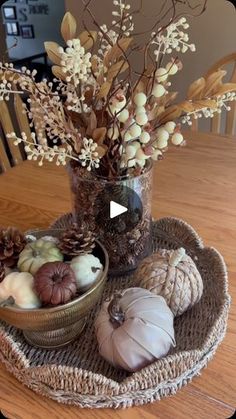 a table topped with a bowl filled with lots of different types of pumpkins and flowers