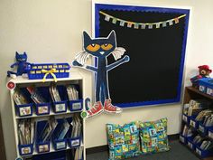 a classroom with bookshelves, toys and posters on the wall in front of it