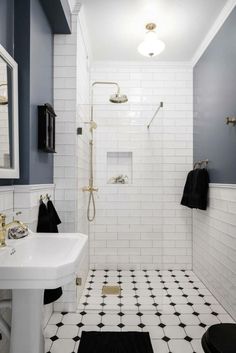 a bathroom with black and white tile flooring and walls, along with a walk in shower