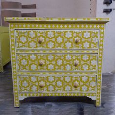 a yellow and white dresser with flowers painted on it