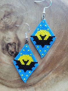 a pair of blue and yellow beaded earrings on top of a piece of wood