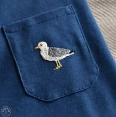 a close up of a bird on a blue shirt with a white and yellow patch