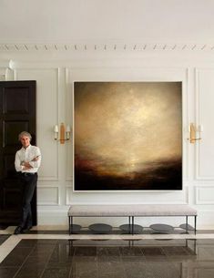 a man standing next to a large painting in a room with black and white flooring