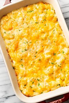 a casserole dish with cheese and parsley in it on a marble surface