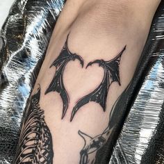 a bat tattoo on the leg of a person with a heart in it's center