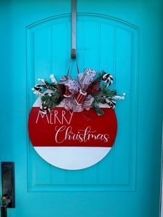 a blue door with a merry christmas sign hanging from it's side and wreath on the front