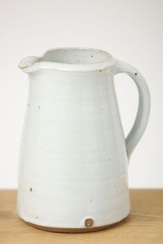 a white pitcher sitting on top of a wooden table