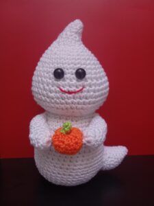 a white crocheted stuffed animal holding a carrot